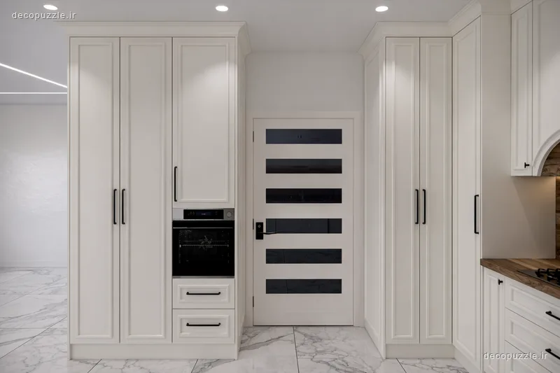 کابینت نئوکلاسیک سفید با فر توکار و کابینت‌های تا سقف در آشپزخانه‌ای روشن